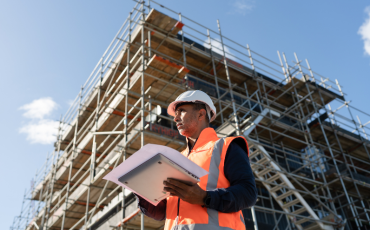 "Project engineer reviewing construction plans at a commercial infrastructure development site"