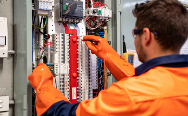 "Electrical engineer inspecting industrial control panel and power distribution system"