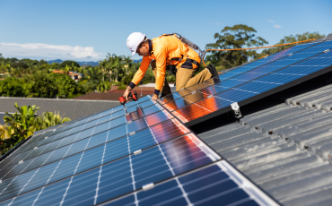 Solar technician installing rooftop solar panels for renewable energy generation